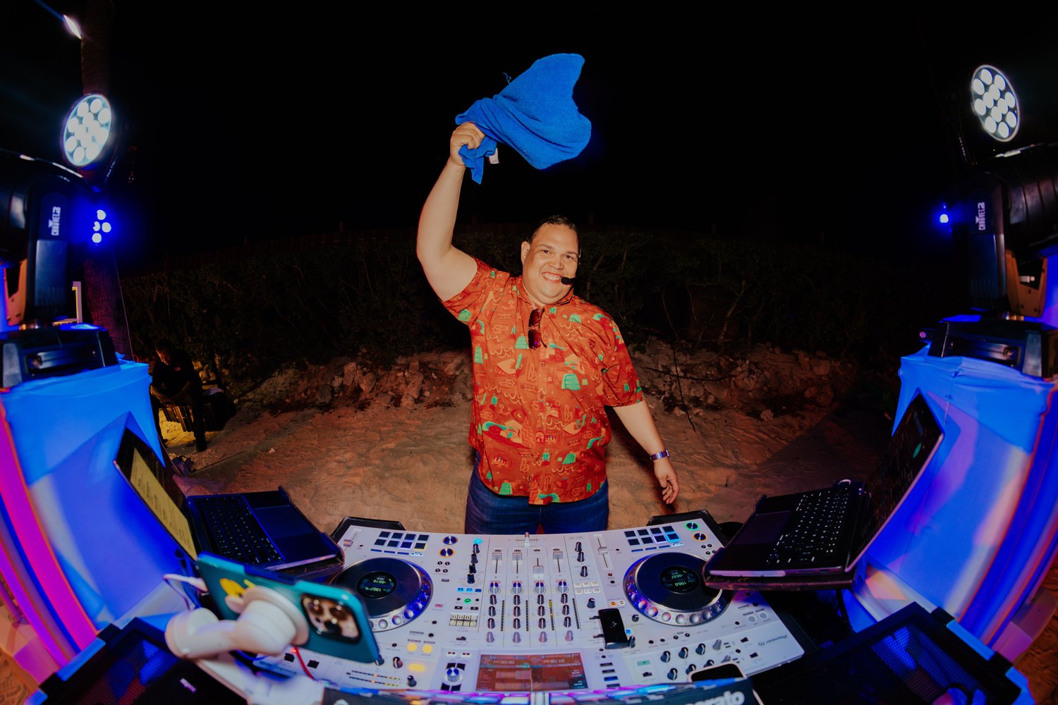 Ruuben smiling and raising a blue towel behind the decks